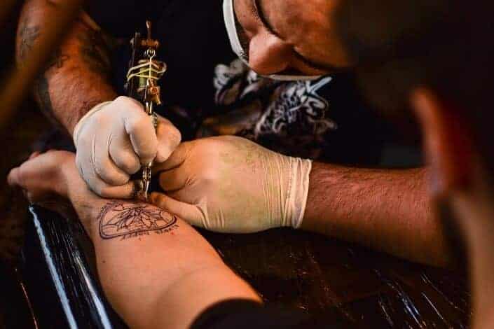 artista del tatuaje que trabaja en una mano